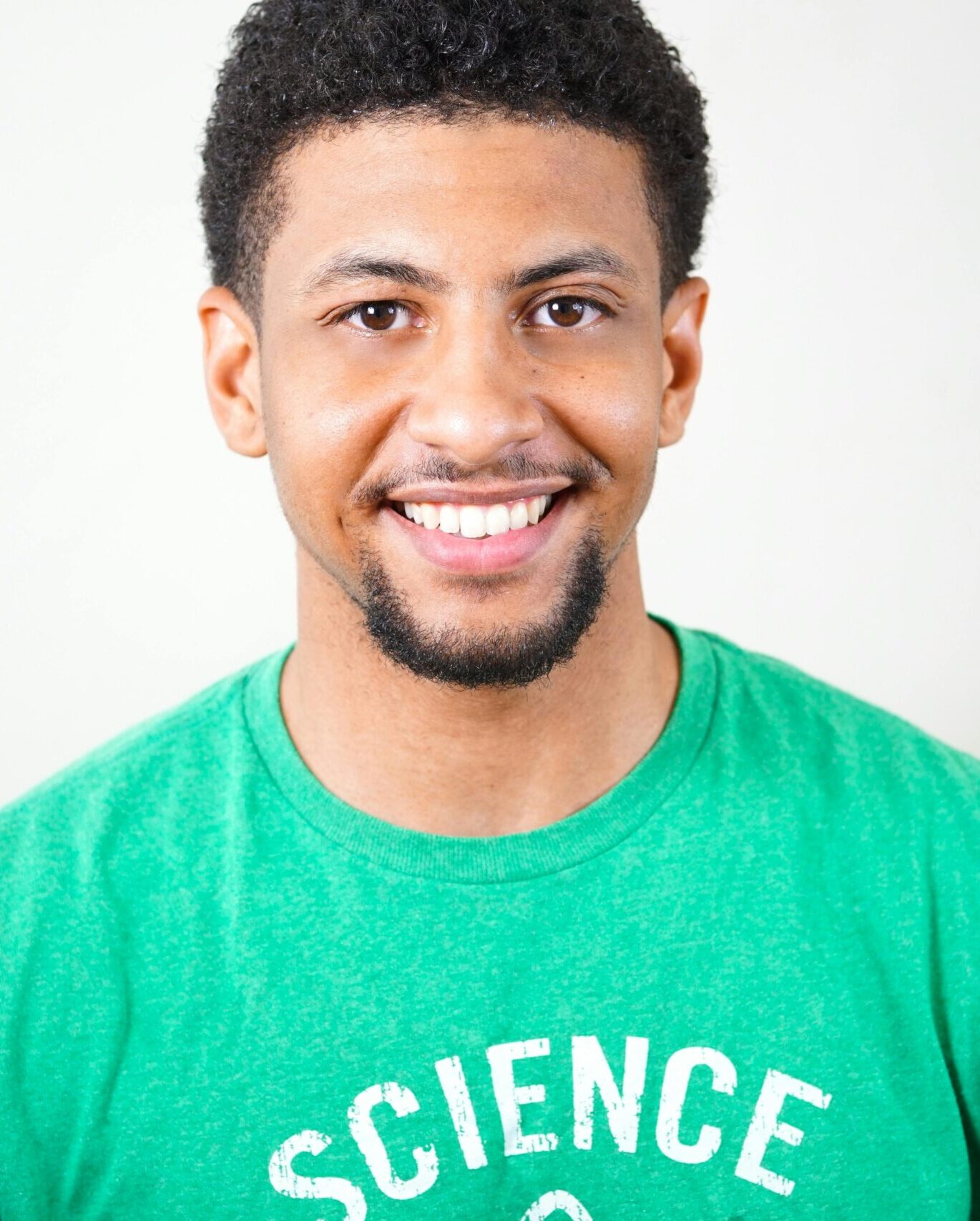 Portrait of a smiling young man wearing a green T-shirt with science text.